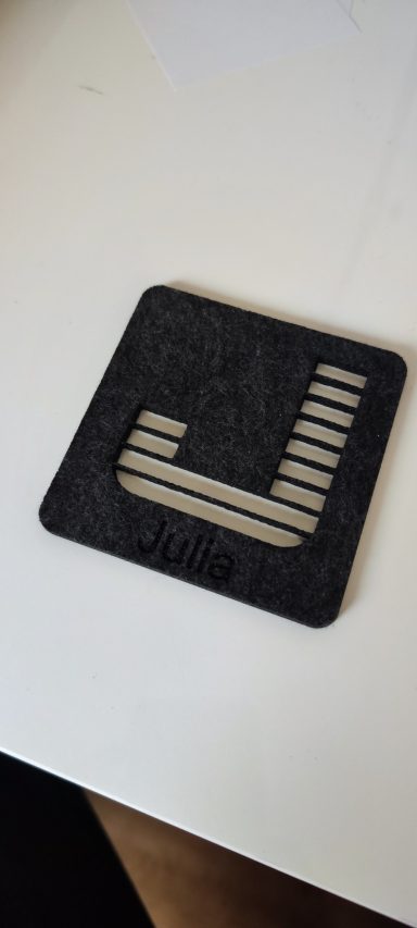 Schwarzes, quadratisches Filz-Tischset mit abgerundeten Ecken, ausgeschnittenen Besteckhaltern und eingraviertem Namen „Julia“.